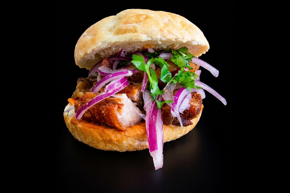 Pan con chicharrón: chicharrón de cerdo, camote y salsa criolla en pan francés